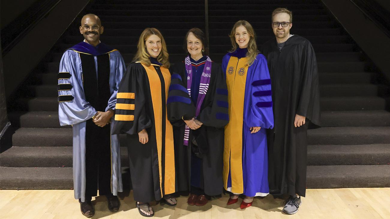 Five faculty wearing regalia standing on steps