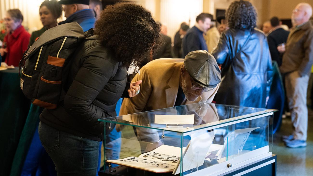 People look at items in a display case in the Bridges Auditorium lobby.