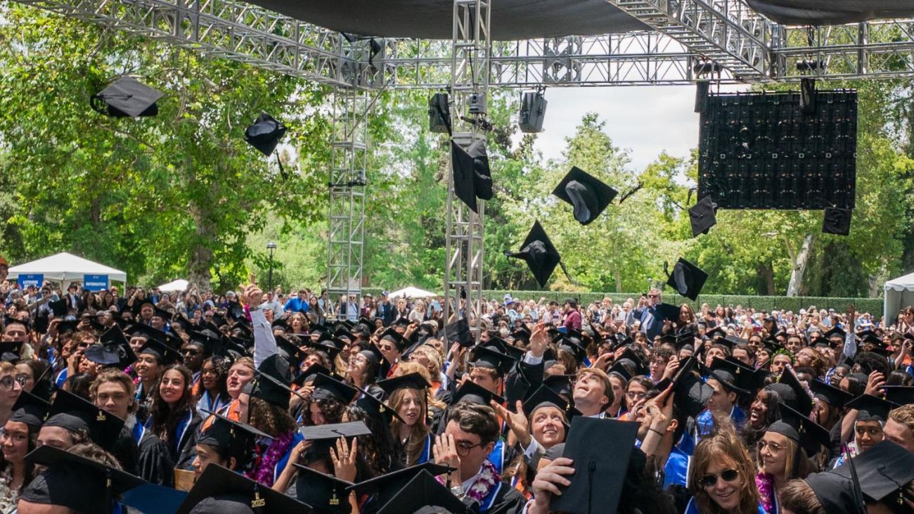 Commencement photo of graduates throwing their caps in the air