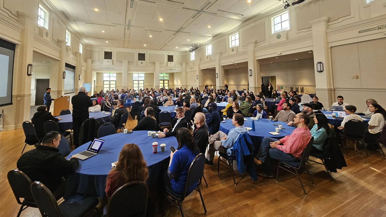 People sitting at round tables watching a presentation.