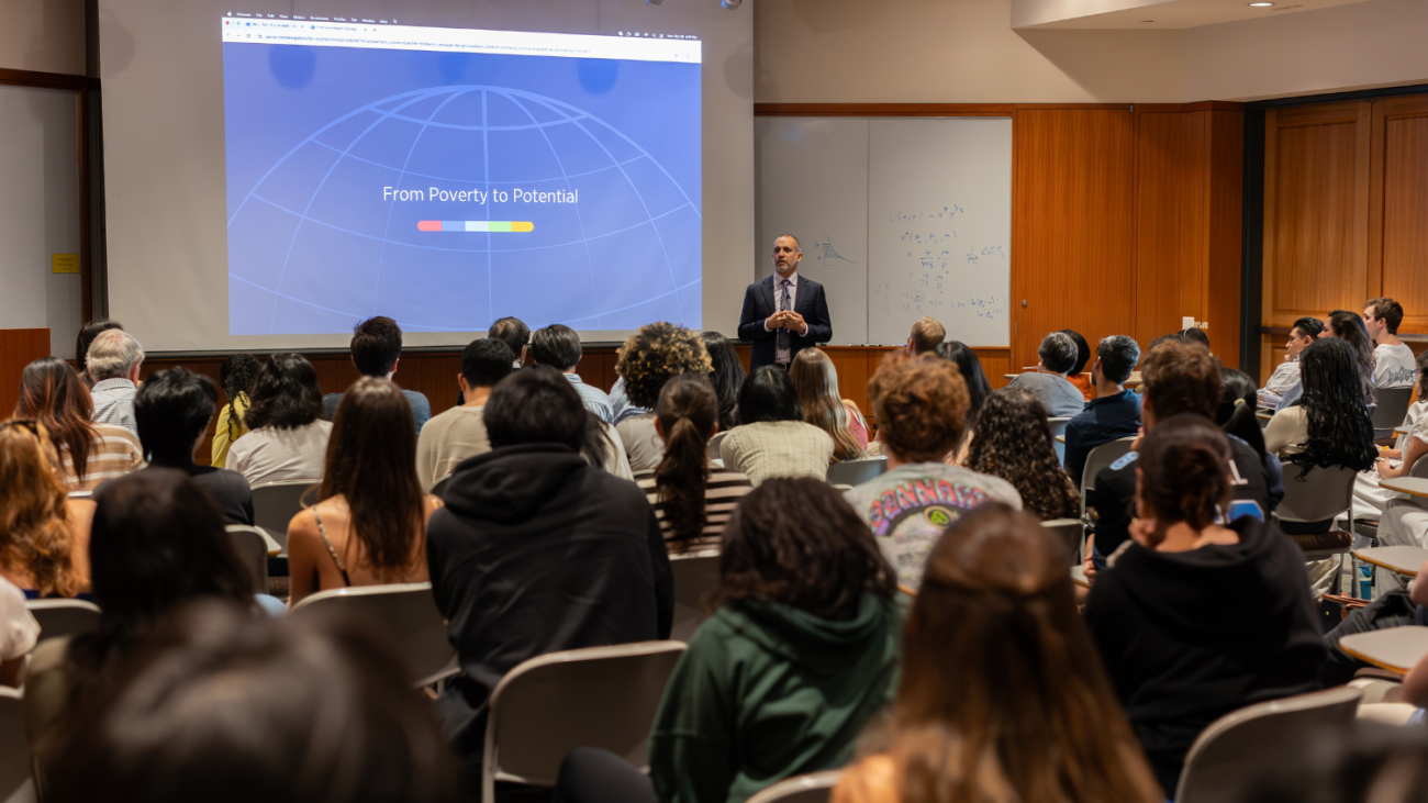 Asim Ijaz Khwaja giving lecture with first slide of the lecture "From Poverty to Potential"