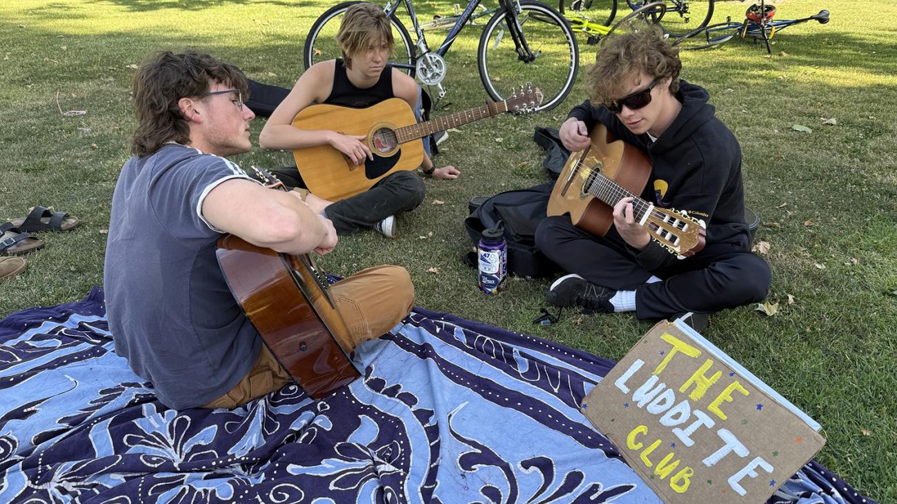 Three students play guitars on Marston Quad.