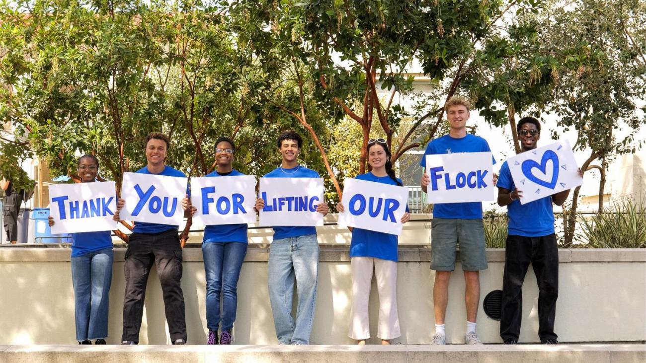 Students hold up signs that say "Thank you for lifting the flock"