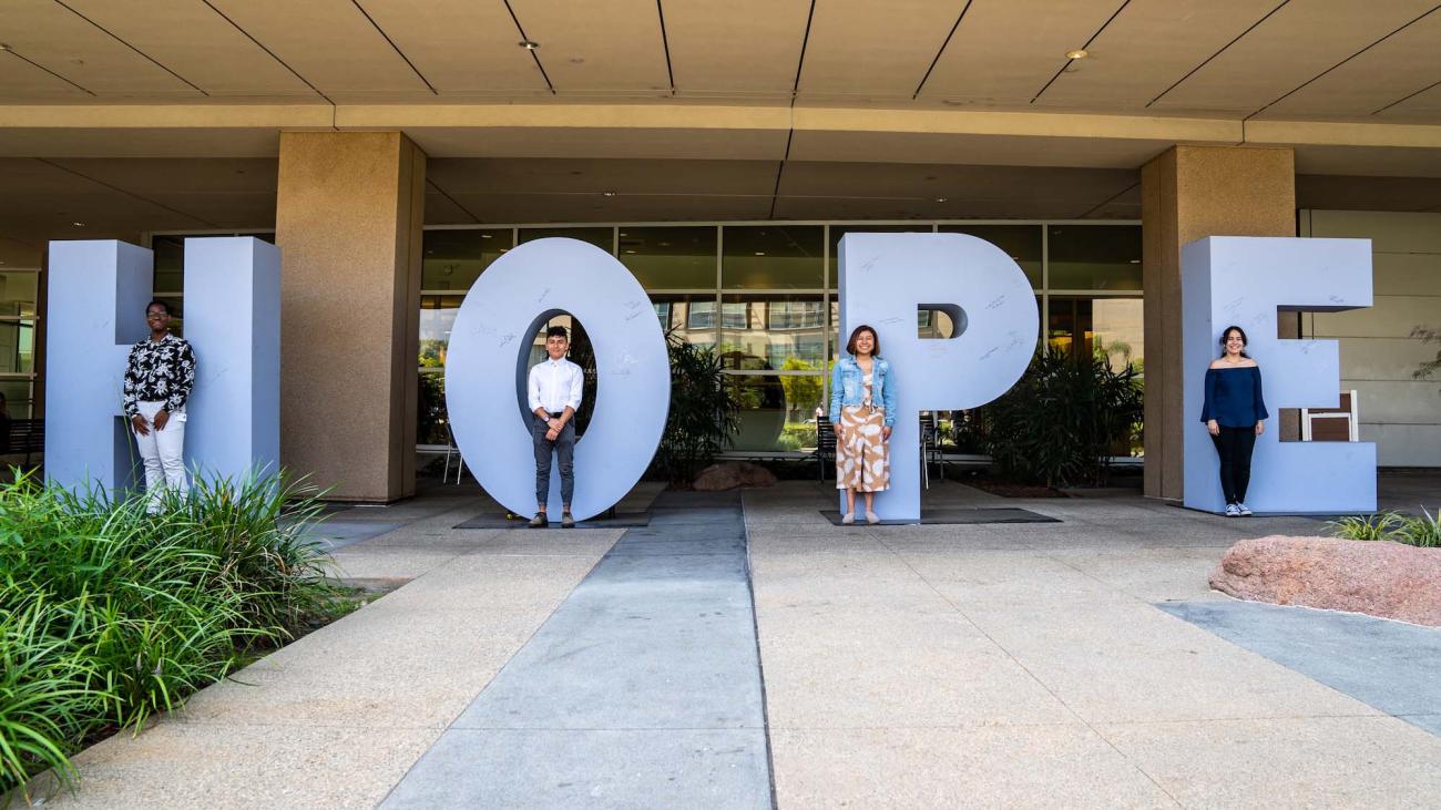 Students stand in front of giant letters that spell HOPE.
