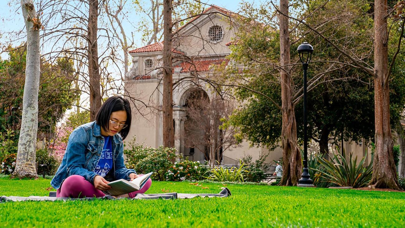 Student reads a book on Marston Quad
