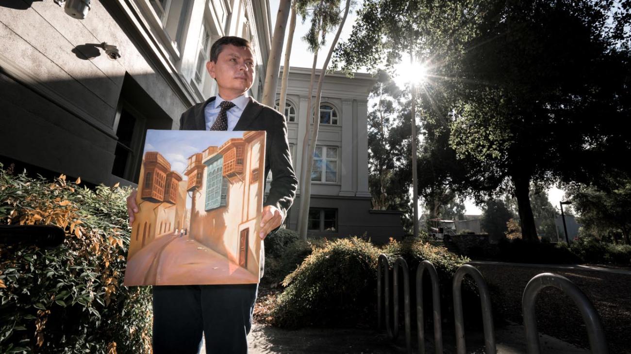 Professor stands with painting of Iraq on Pomona's campus.