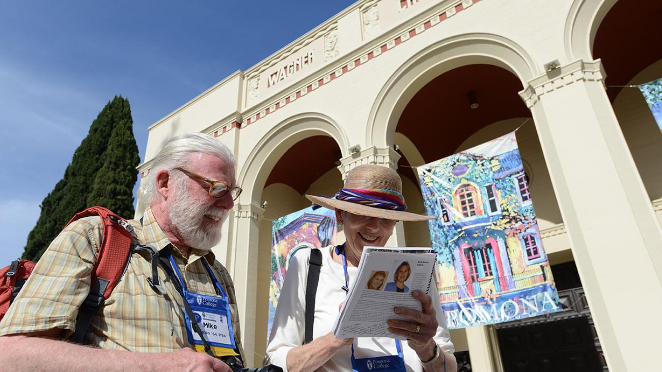 Pomona College alumni consult their Alumni Weekend guide in front of Bridges Auditorium